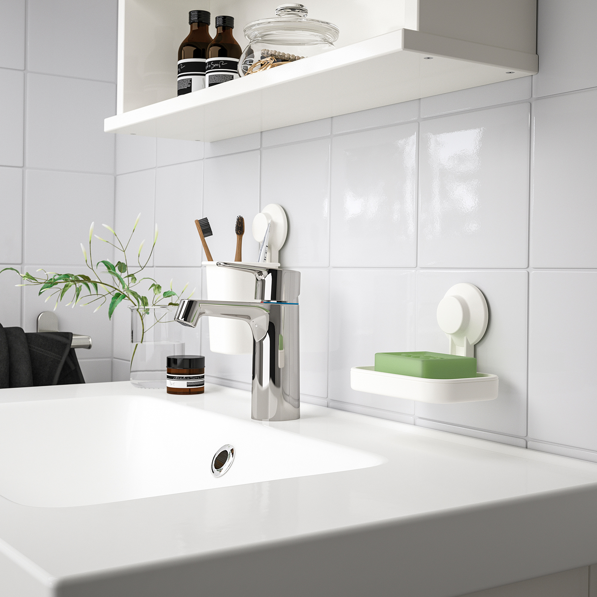 Modern white bathroom sink with chrome faucet. Small TISKEN green soap dish, toothbrush holder, and plant. Clean, minimalist design.