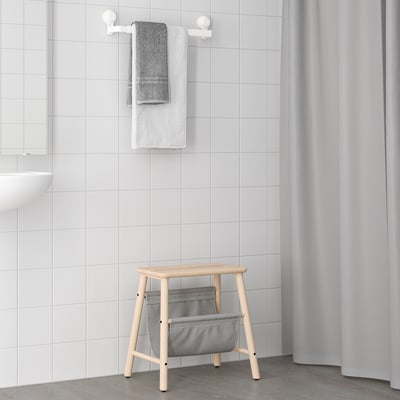 Wooden bath stool with gray TISKEN bag, perfect for bathroom storage.