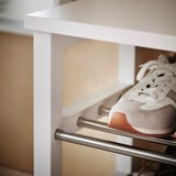 White TJUSIG shoe rack with light sneakers on metal bars.