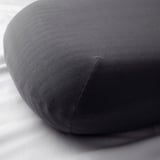 Close-up of round, grey, high-quality fabric pillow with smooth texture and tight stitching.