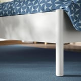 Modern white bed frame with sturdy legs and patterned mattress, showcasing quality design and construction.