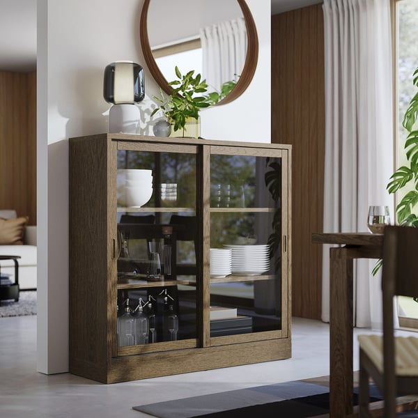 TONSTAD cabinet with glass doors, oak finish, rectangular shape, modern design, medium size, displayed near a dining table.