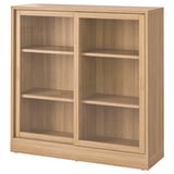A TONSTAD wooden cabinet in oak color. It sliding glass doors, three shelves, and a classic design.