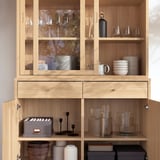 Glass cabinet with wine glasses, bowls, candles, and vases.
