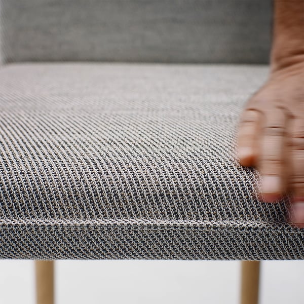 Close-up of TONSTAD dining table with textured, neutral fabric and gold legs.