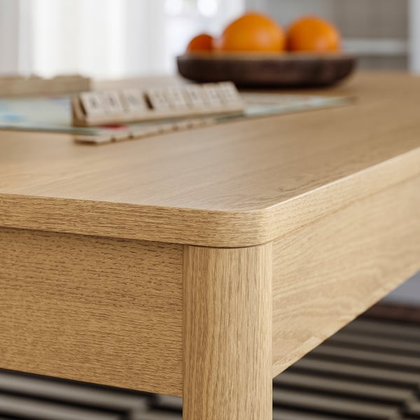Closeup of TONSTAD dining table edge, showcasing smooth, rounded designs and natural oak veneer texture.