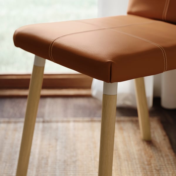 Modern dining chair with cushioned seat and sleek wooden legs.