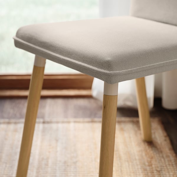 Modern, cushioned stool with pale grey fabric and light wood legs, showing quality and comfort.