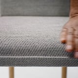 Close-up of TONSTAD table; textured grey fabric, sturdy wooden leg, elegant design.