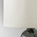 Modern lamp with smoky glass base and sleek beige shade. Quality craftsmanship evident in glass and fabric.