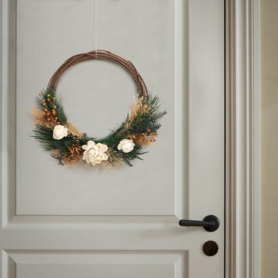 Wreath of dried flowers and plants hangs on a door, welcoming visitors with natural beauty.