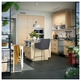 Modern kitchen with light wood cabinets, stainless steel appliances, and a grey upholstered barstool.