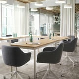 Modern meeting room with gray swivel chairs, wood tables, papers, and natural light.