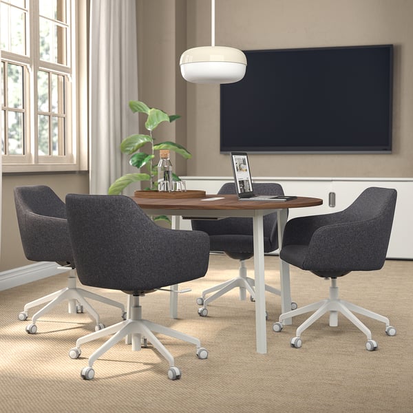 Small TOSSBERG gray swivel chairs with white legs and high back support surround a round wooden table near a large tv on a beige wall in a cozy room.