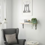 Cozy corner with gray armchair, side table, books, plant, brooklyn bridge print.
