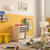 Bright childrens playroom with TROFAST storage in natural wood and white. Mesh and plastic boxes, a yellow stool, and wooden toys.