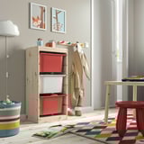 Kids play area with TROFAST storage, red boxes, wood, colorful rug. Low, bright, organized.