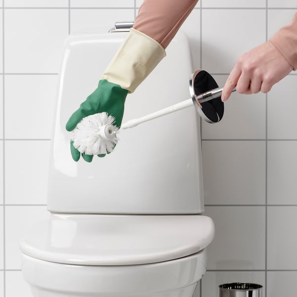 Person cleaning a toilet with a white brush wearing green gloves.