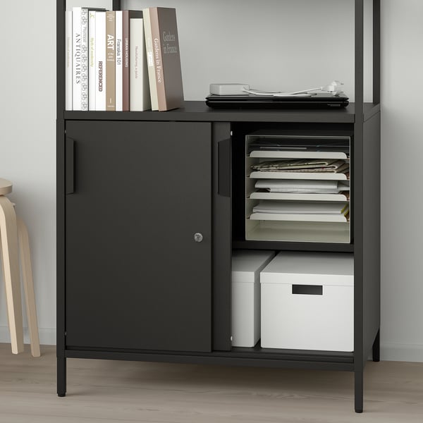 Black office cabinet with sliding doors and open shelves, storing files and books.