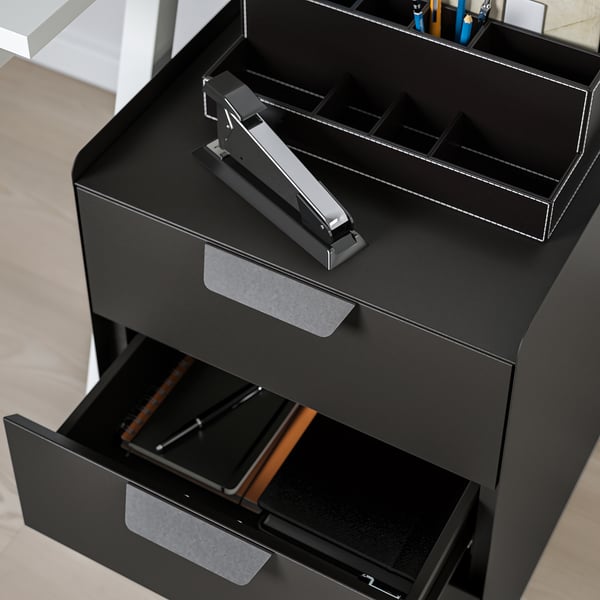 Black office storage unit with open drawer and stapler on top.