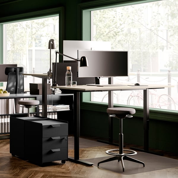 Modern home office with TROTTEN desk, chair, storage, adjustable height, lockable units, green walls, wood floor, large window.