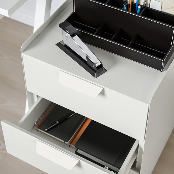 White office storage unit with open drawers, black trays, and pen organizer on top.