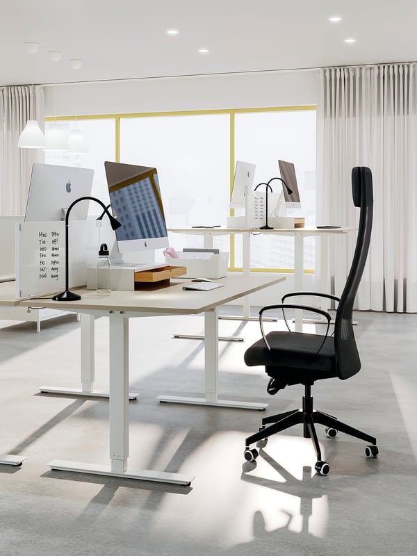 Modern office space with TROTTEN desk, black chair, apple imac, laptop, and accessories. Clean, minimalistic design with natural light.