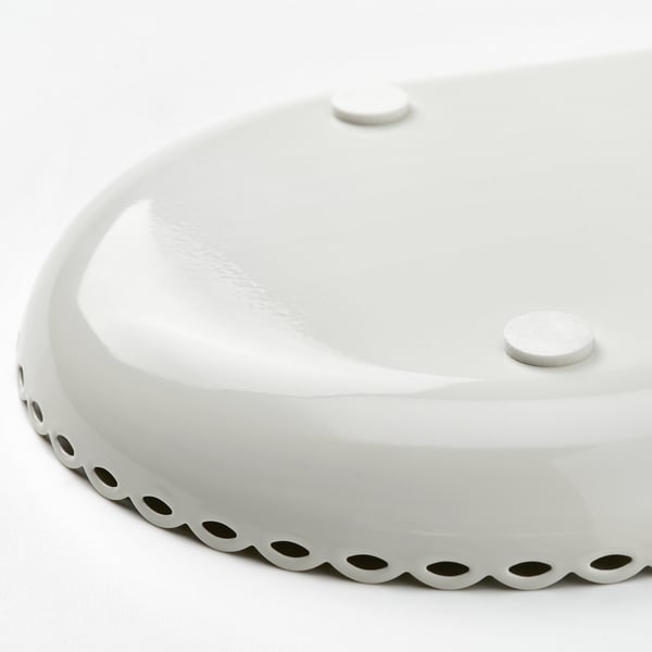 Elegant white scalloped-edge candle dish, gleaming under soft light.