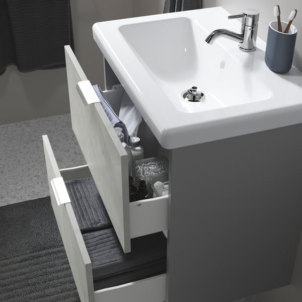 Modern bathroom with TVÄLLEN sink, open drawer showing toiletries, fits base cabinet, includes drain stopper.