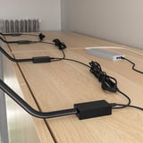 Wooden desk with power strips and bundled cables, including black cords and a gray hub, indicating organized electronics setup.