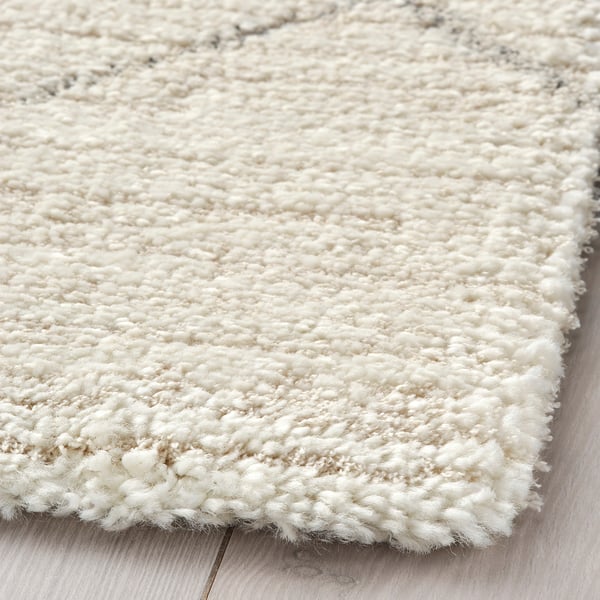 Close-up of soft, plush rug with high-quality texture. Off-white color, thick pile, and intricate weave.