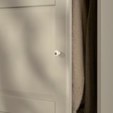 White wardrobe door with rounded panel edges, featuring a soft-close hinge for smooth and silent closure, positioned beside folded grey textiles.