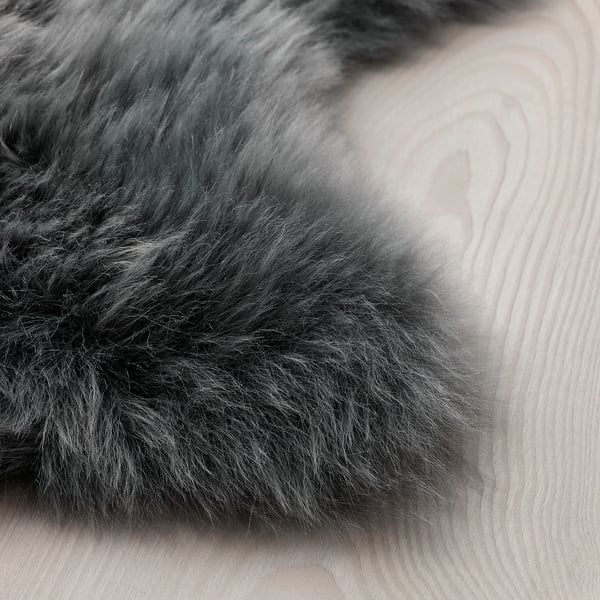 Soft, plush sheepskin rug laid out on a light wooden floor. Texture appears thick and luxurious, inviting comfort.