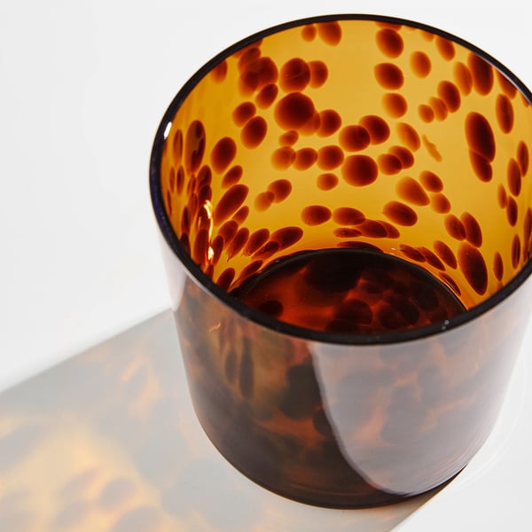 Glass vase with black interior speckled orange, lit softly.