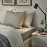 ULLVIDE bedding: soft cotton blend pillows on bed, lamp, wine.