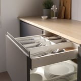 Open kitchen drawer reveals an organized cutlery tray, keeping utensils neat and accessible.