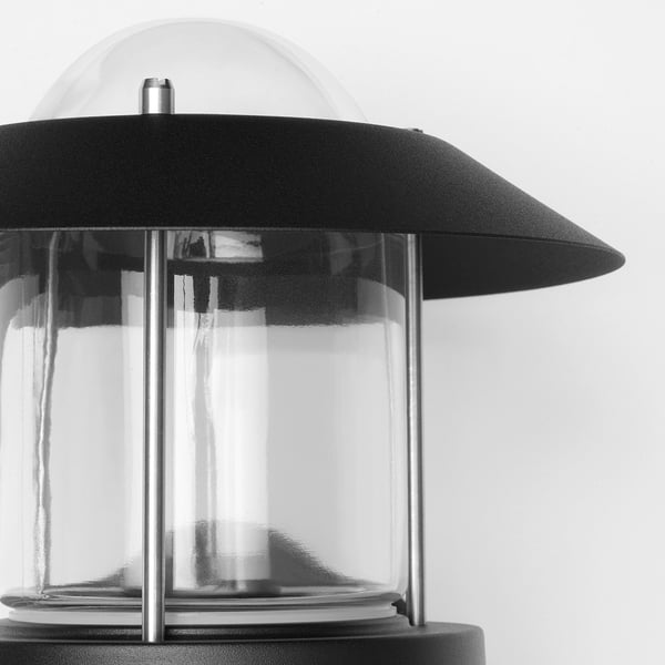 Black wall lamp with clear glass shade, featuring durable metal construction, suitable for outdoor use.