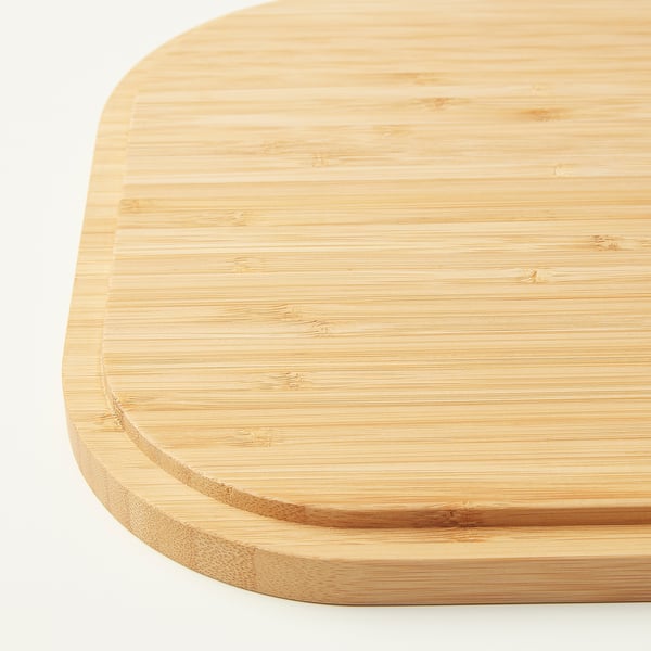 Dense, polished bamboo chopping board, light grain visible, slightly rounded edges, clean, smooth surface.