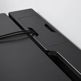 Close-up of black gaming desk with sleek, matte finish and cable management tray.