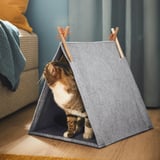 Cat inside grey felt tent house, looking out. Part of UTSÅDD series for pet comfort and relaxation.