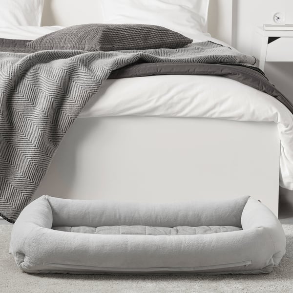 A cozy dog bed, UTSÅDD, a bolstered edge for support and relaxation. The soft, machine-washable cover is perfect for indoor pets.