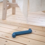 Blue dog toy on wooden floor, shaped like an allen key. Part of UTSÅDD range by IKEA.