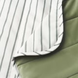 A close-up of a striped blanket with a smooth, soft texture on one side and a fleecy, warm texture on the other, highlighting its quality and design.