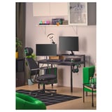 Gaming setup: desk, chairs, dual monitors, accessories, plants.