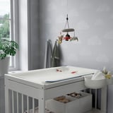 Baby nursery with VÄDRA mat, mobile, and plant.