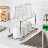 Kitchen sink with mugs, glasses, and soap dispenser.