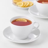 Two cups of tea with lemon slices on a white table. The durable cups are made of feldspar porcelain, suitable for everyday use and gatherings.