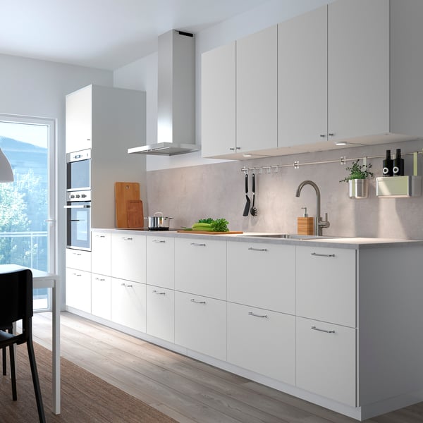 Modern kitchen with white cabinets, stainless steel appliances, and gray countertop. VALLSTENA cabinets dominate space.