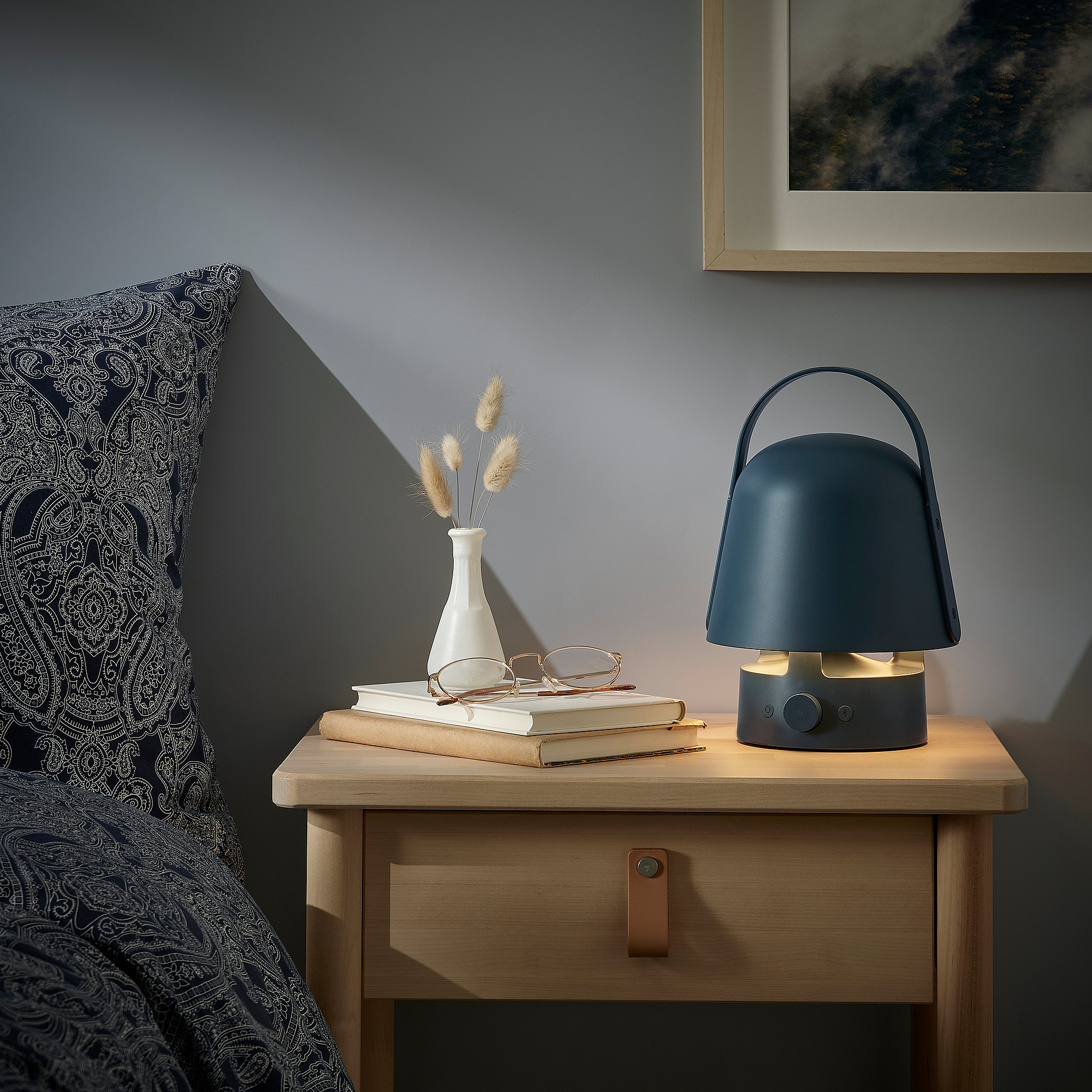 VAPPEBY lamp on bedside table with dried flowers and books.
