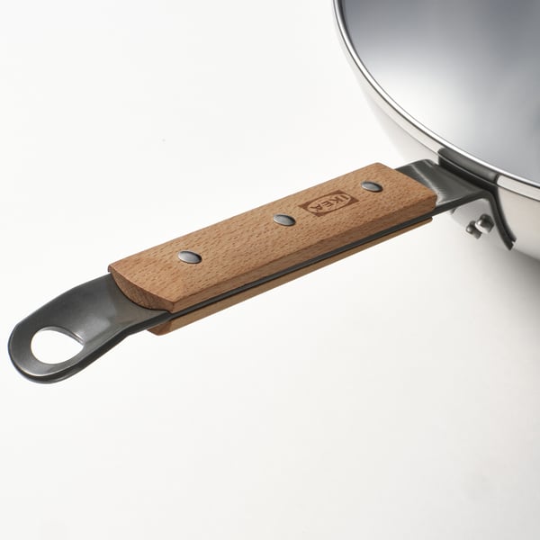 Displays a close-up of a VARDAGEN wok handle, featuring a sturdy, wooden grip and a secure metal attachment, emphasizing durability and quality.